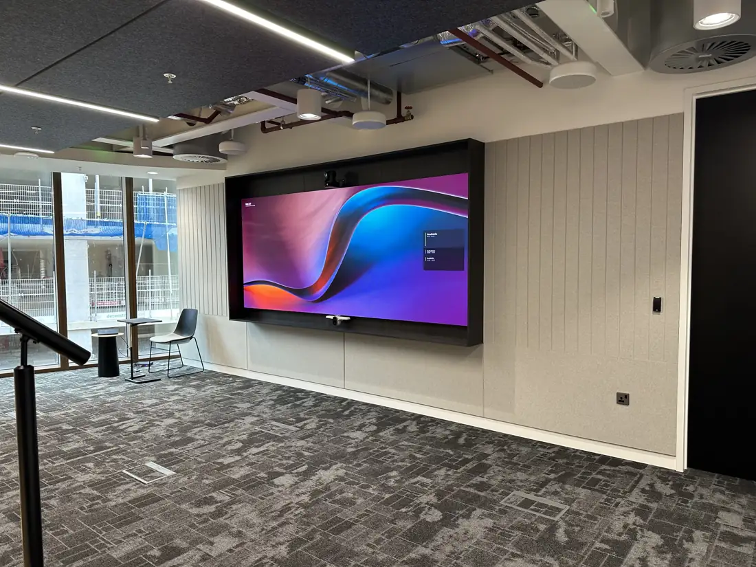 Open plan office with a large wall mounted screen