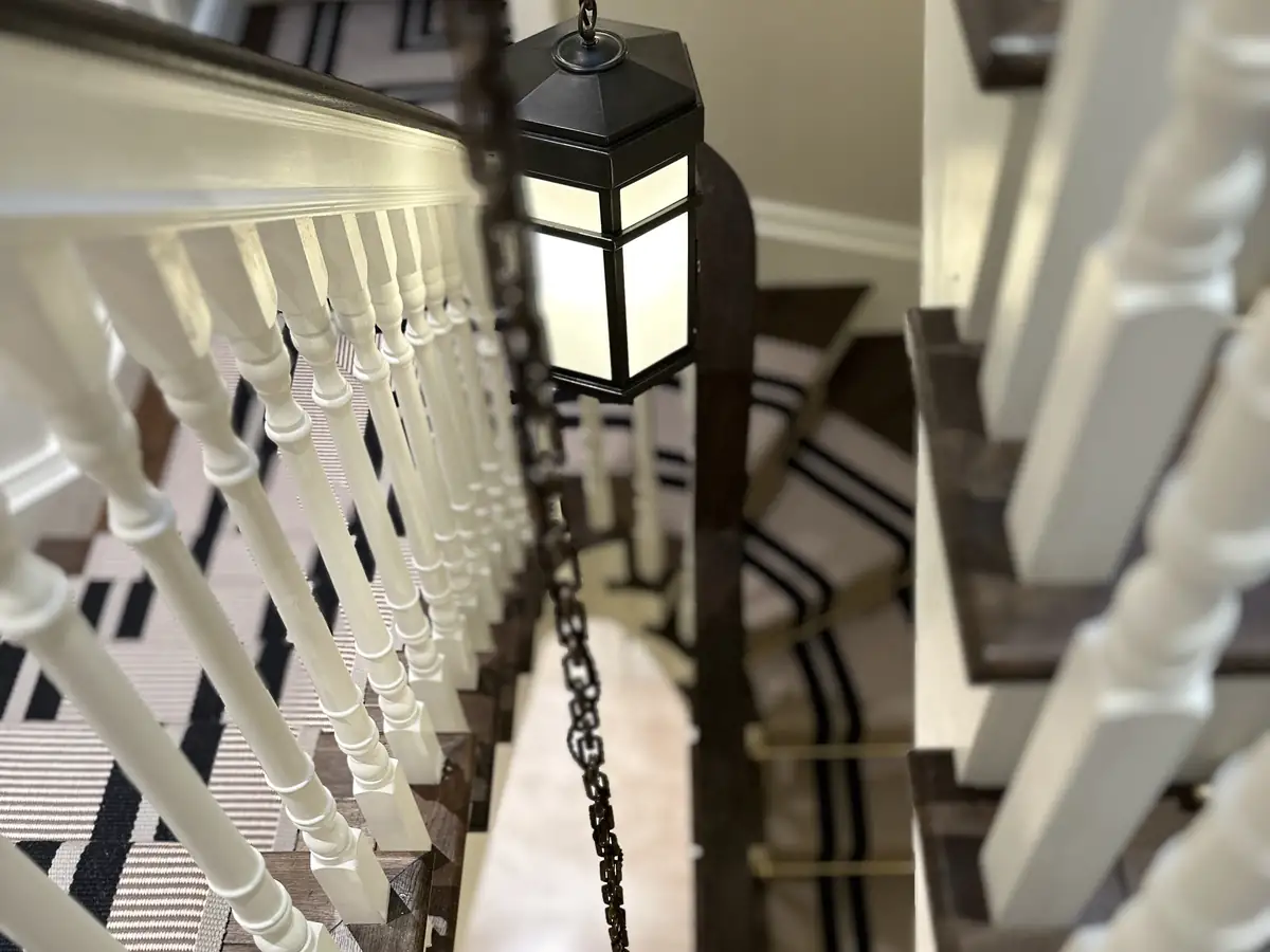 Staircase with white spindles lit by a hanging lantern
